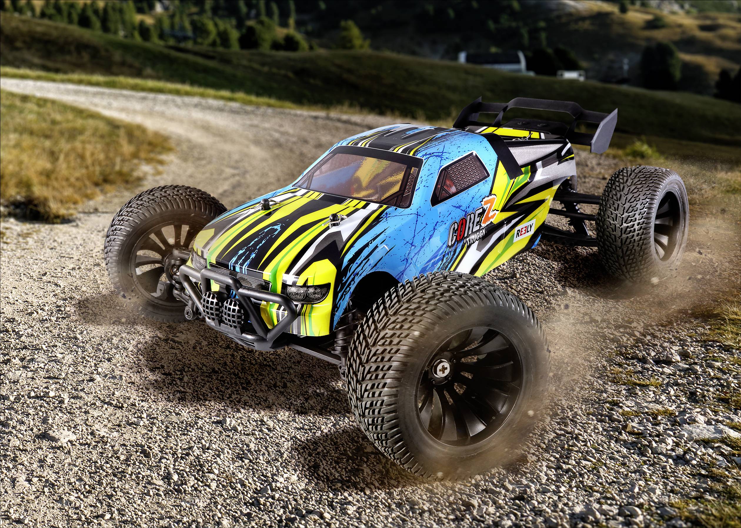 Ein ferngesteuertes Auto mit buntem Design fährt schnell auf einem Schotterweg und wirbelt Staub auf. Hintergrund zeigt eine Landschaft.