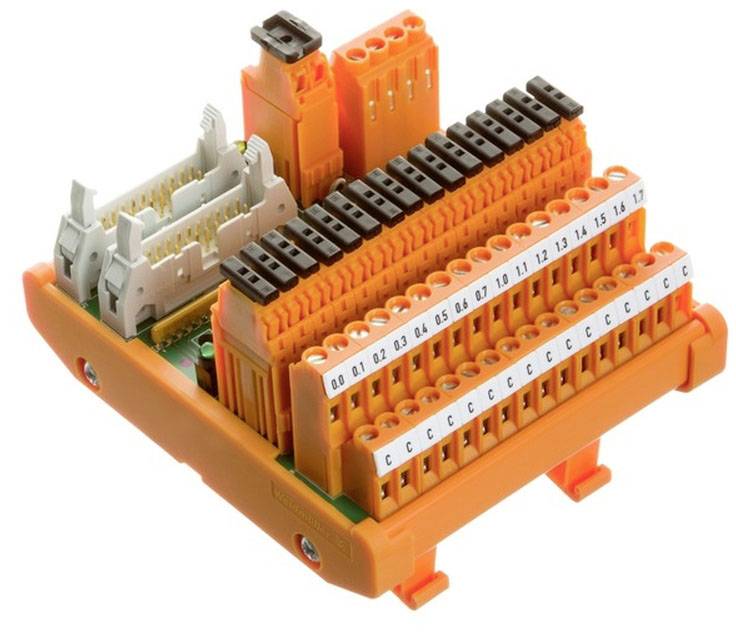 Orangenes elektrisches Klemmterminal mit nummerierten und beschrifteten Anschlüssen, das auf einer grünen Basis befestigt ist.