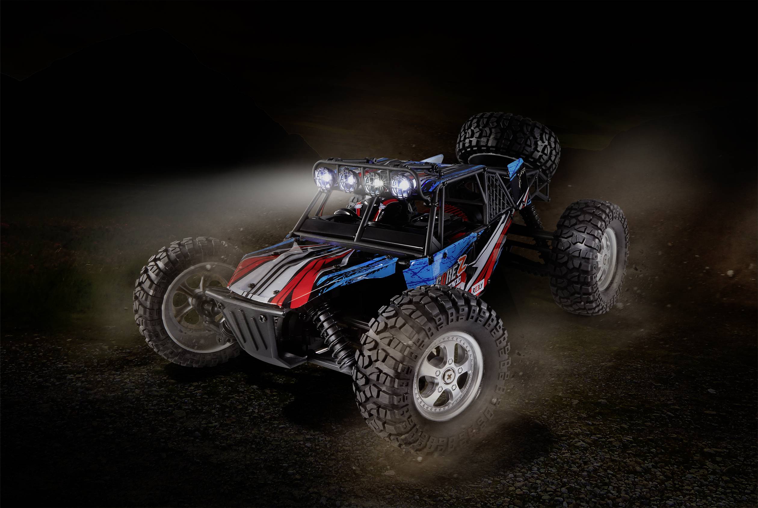 Ein ferngesteuertes Auto mit leuchtenden Scheinwerfern fährt auf einem dunklen, staubigen Weg. Es hat ein sportliches Design und große Reifen.