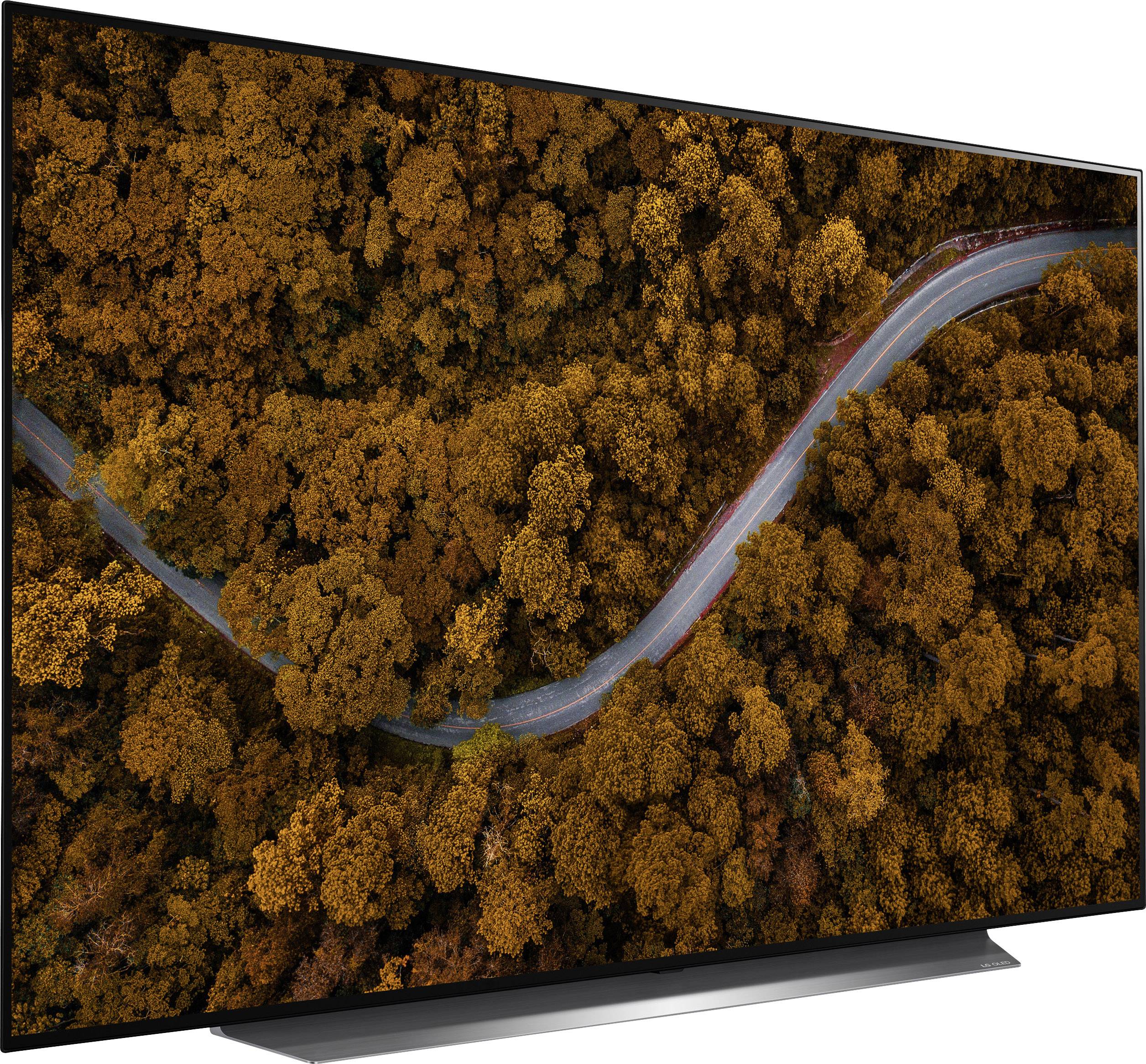 Eine Luftaufnahme zeigt eine kurvige Straße, die sich durch einen herbstlich gefärbten Wald mit orangefarbenem Laub windet.