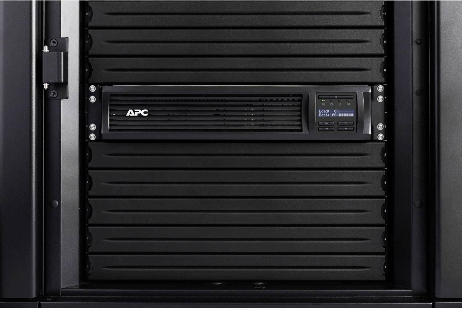 'APC' USV-Einheit in einem Serverrack, zeigt Betriebsanzeige mit blauem Bildschirm rechts, stabilisiert Stromversorgung für IT-Geräte.