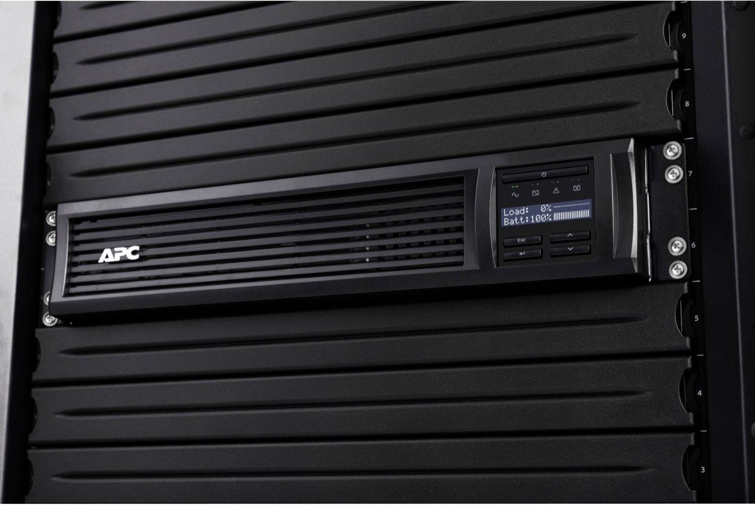 APC USV-Anzeige auf einem schwarzen Server-Rack, zeigt 'Laden: 98%' und 'Batterie: 100%'.