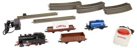 Eisenbahnset mit Gleisen, einer Lokomotive, einem "Zirkus"-Güterwagen, einem blauen Tankwagen, einem braunen offenen Wagen, einem Stromadapter und einer Fernbedienung mit rotem Knopf.