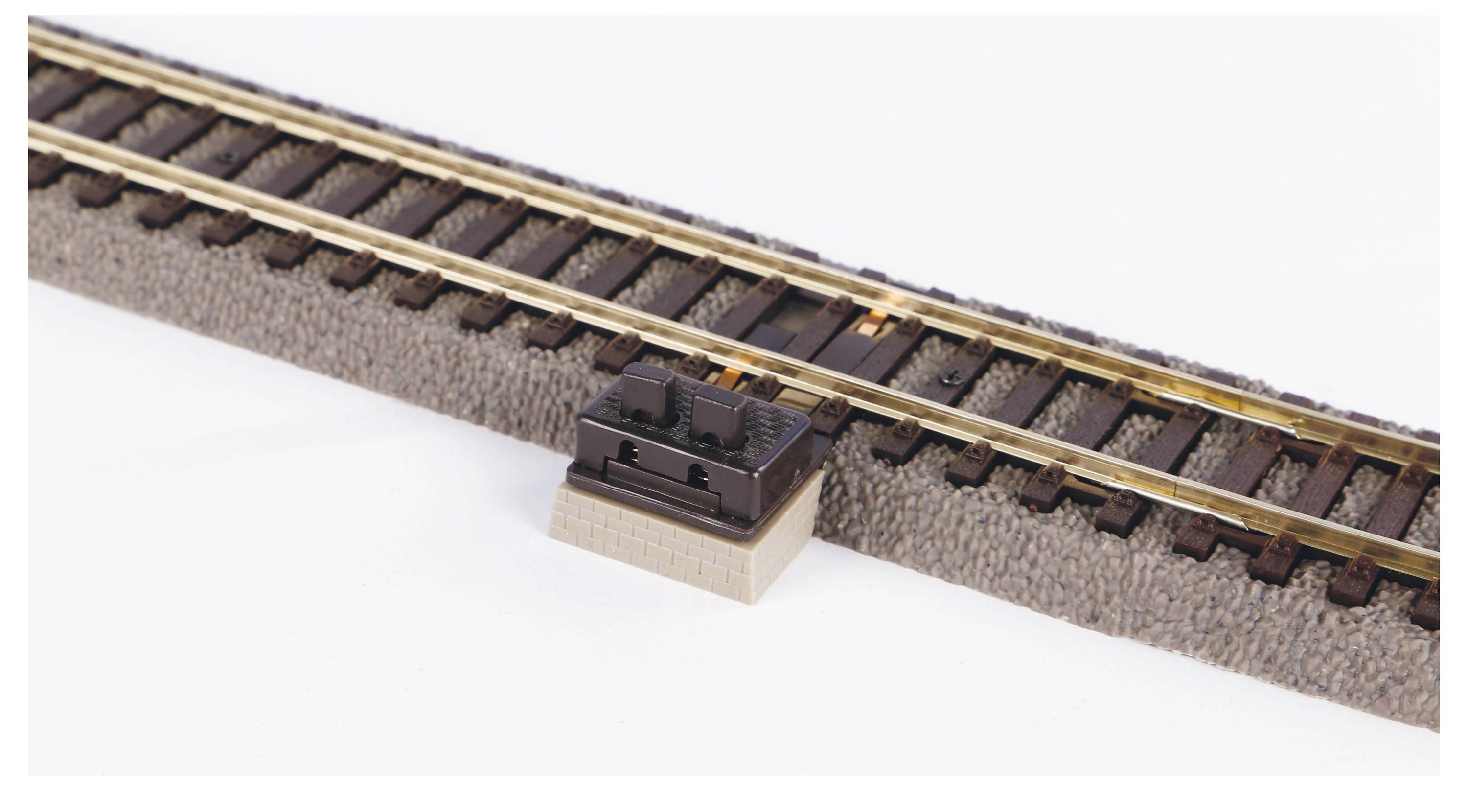 Ein einzelnes Modellbahngleisstück mit zwei Schienen, auf einem rechteckigen Sockel, beige und braun, auf hellem Hintergrund.