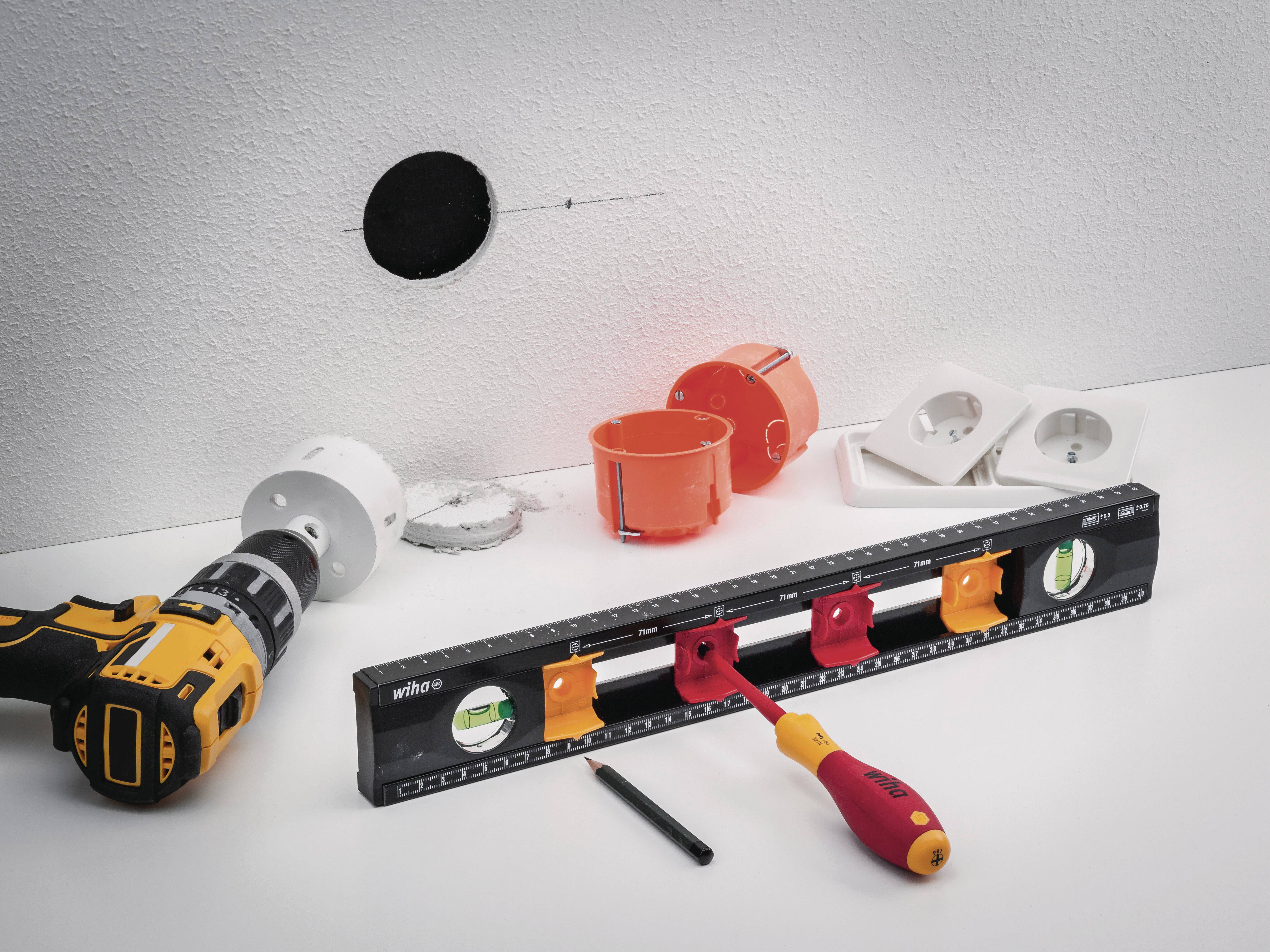 Werkzeuge für die Installation von Steckdosen an einer Wand. Bohrmaschine, Wasserwaage, Schraubendreher und Steckdosen-Einsätze.