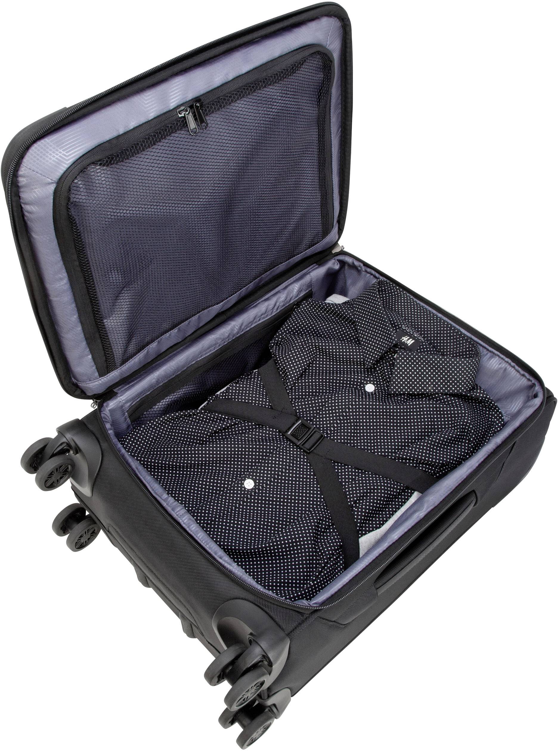 Ein offener Koffer mit einer gepunkteten Hemdbluse, die durch Gurte fixiert ist, zeigt effizientes Packen für Reisen.