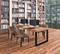 Ein moderner Bibliotheksraum mit Holzregalen voller Bücher, großen Fenstern und einem langen Tisch mit vier Computern und Stühlen.
