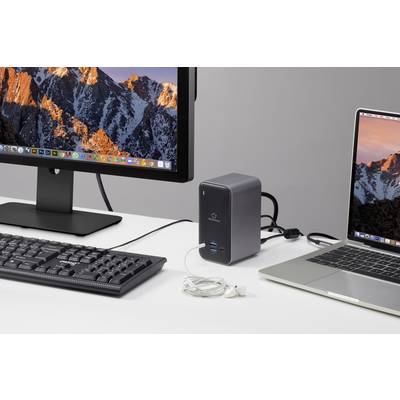 'Computersetup mit zwei Monitoren, einer Tastatur, einem Laptop und einem Ladegerät auf einem Schreibtisch.'