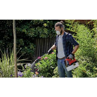 Ein Mann mit Schutzmaske sprüht Pflanzen in einem Garten mit einem Handgerät. Im Hintergrund sind verschiedene Büsche und Bäume zu sehen.
