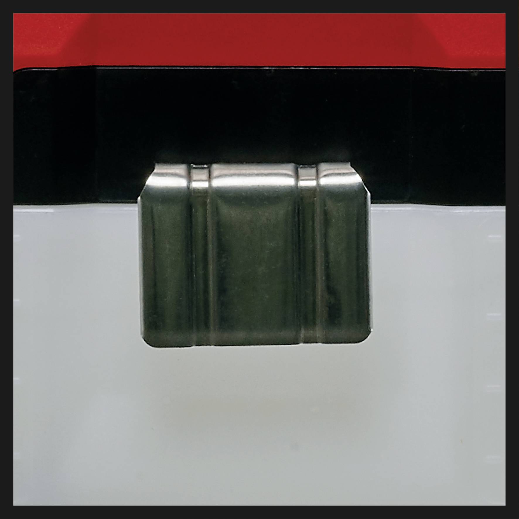 Ein transparentes Kunststoffbehälter mit einem schwarzen und roten Deckel. Eine Metallklammer befestigt den Deckel am Behälter.