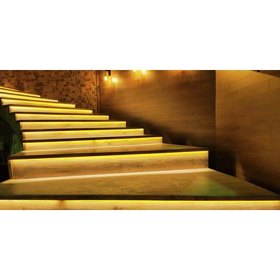 Treppe mit warmem Licht, das die Stufen hervorhebt, in einem gedämpft beleuchteten Raum mit Ziegel- und Holzwänden.