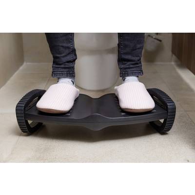 Person mit rosa Hausschuhen steht auf Fußstütze im Badezimmer.