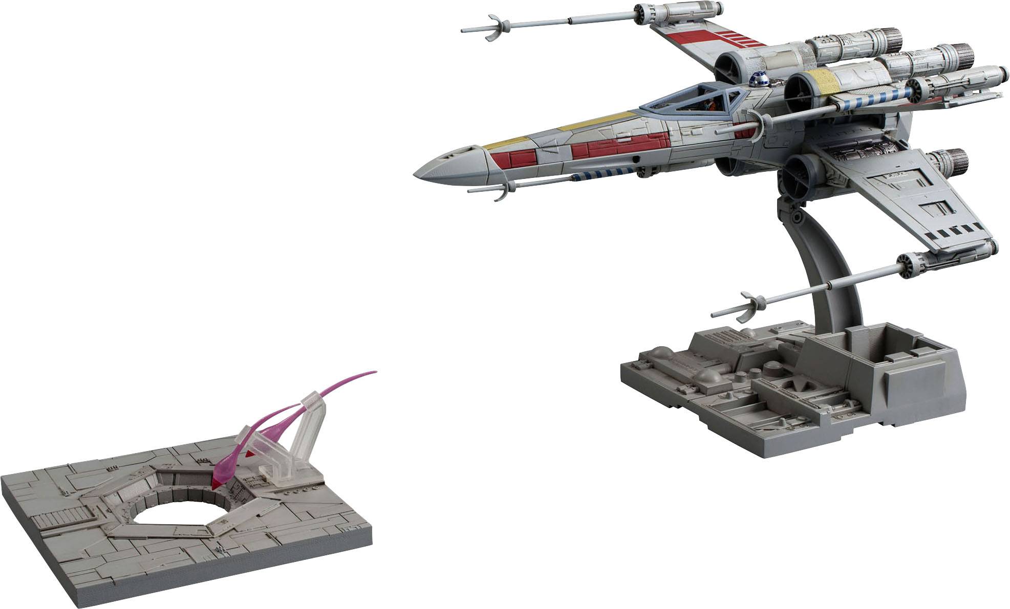 Ein detailliertes Modell eines futuristischen Raumfahrzeugs mit X-förmigen Flügeln auf einem Präsentationsständer neben einer Startrampe.