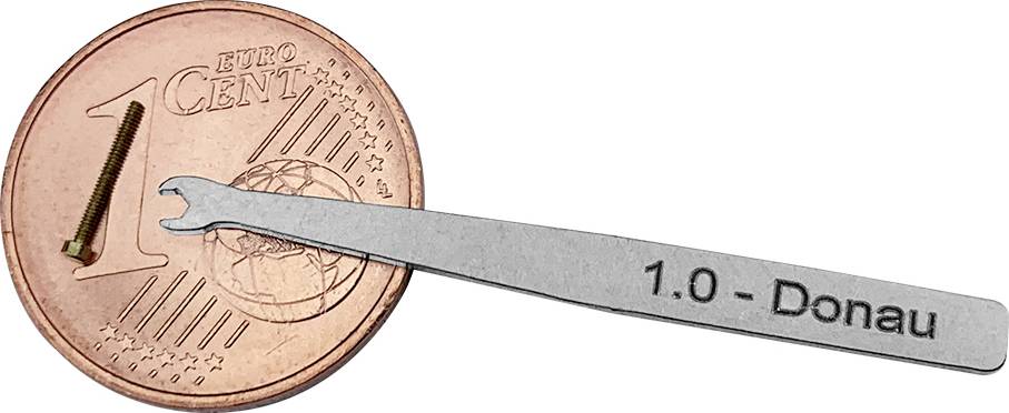 '1 Eurocent Münze zeigt Größenverhältnis: winzige Schraube und kleiner silberner Werkzeugschlüssel mit Gravur "1.0 - Donau".'