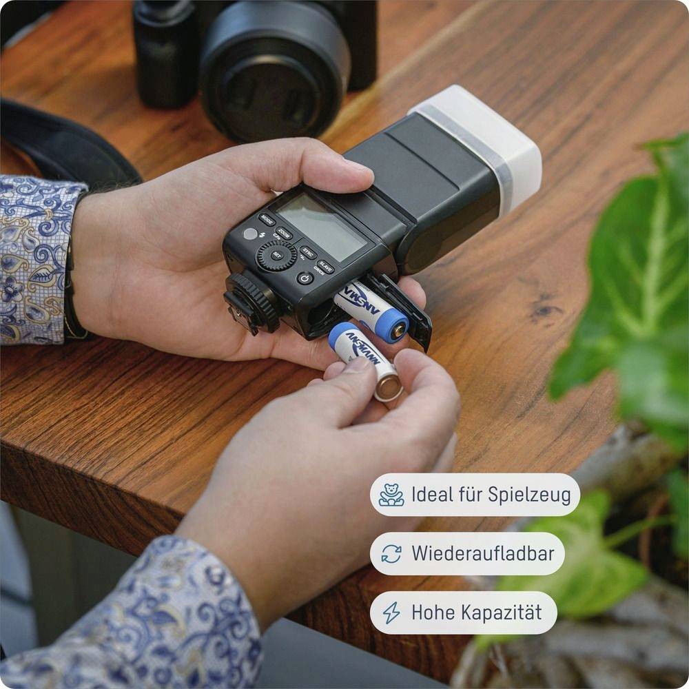 „Person, die Batterien in einen Kamerablitz auf einer Holztischoberfläche einlegt. Icons heben hervor: Ideal für Spielzeug, Wiederaufladbar, Hohe Kapazität."