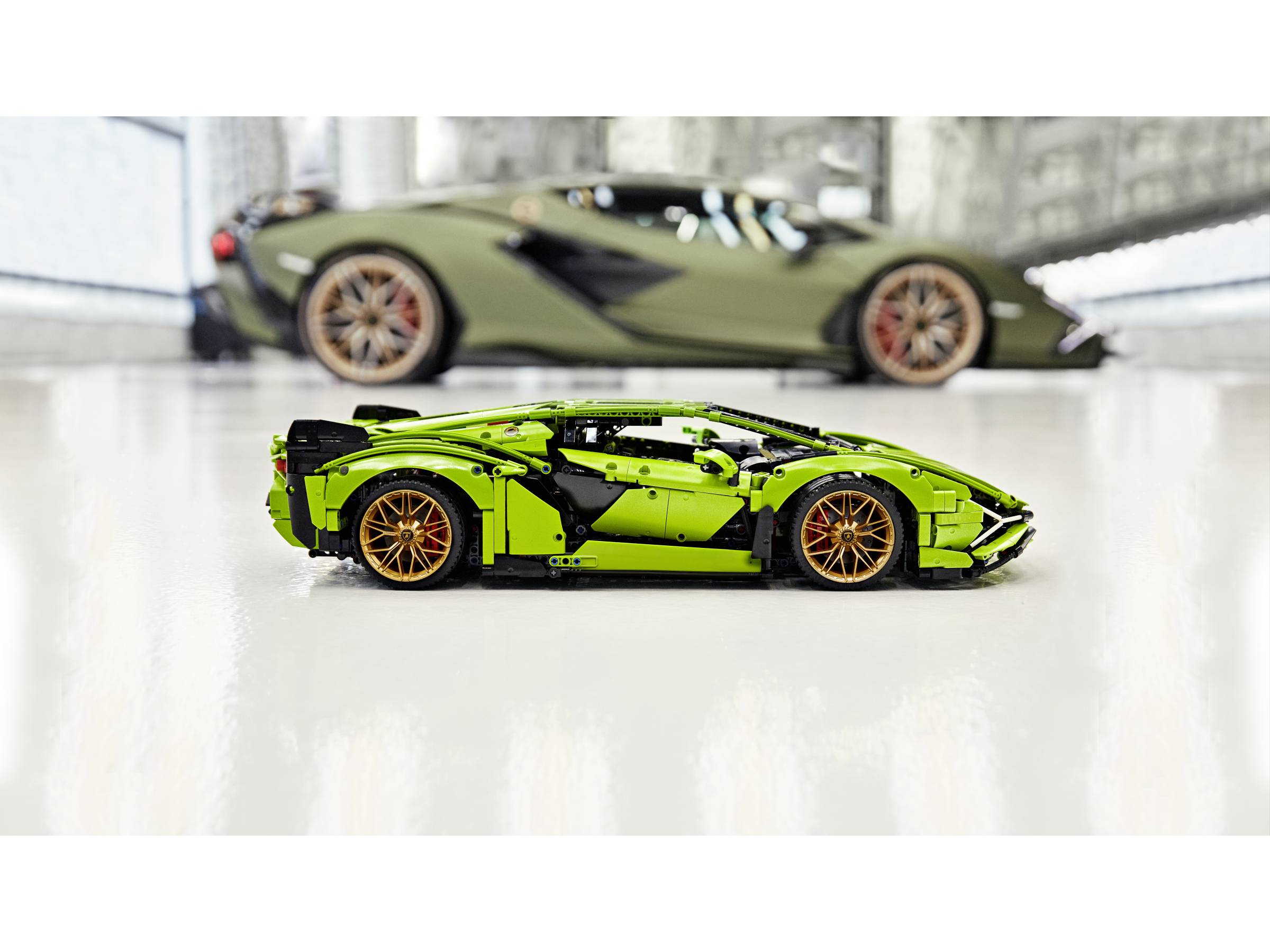 Ein grünes Modellauto aus Bausteinen steht im Vordergrund, mit einem verschwommenen grünen Sportwagen im Hintergrund.