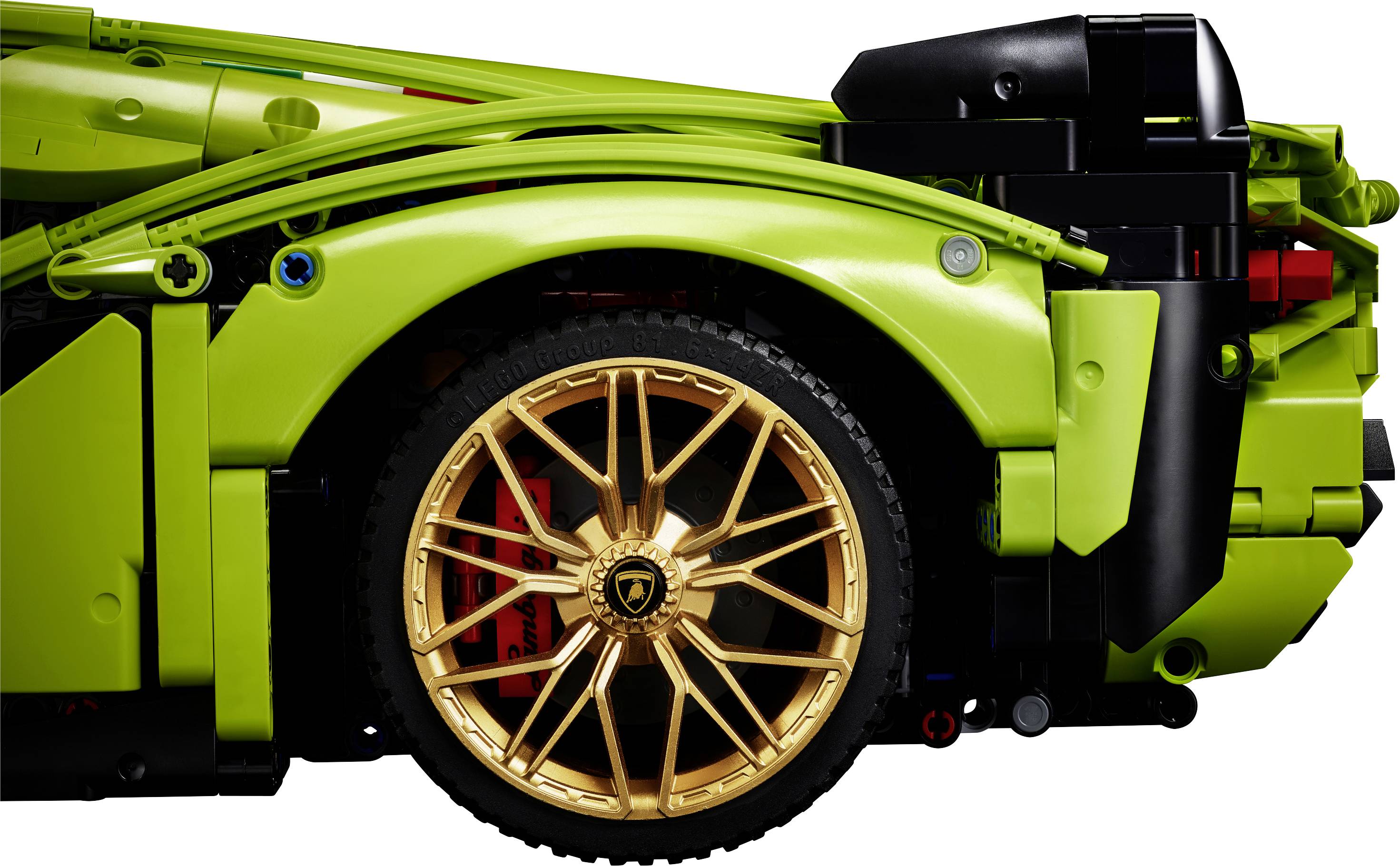 Ein grünes LEGO-Modellauto mit goldenen Felgen, die das Hinterrad zeigen. Das Foto betont die Details der Konstruktion.