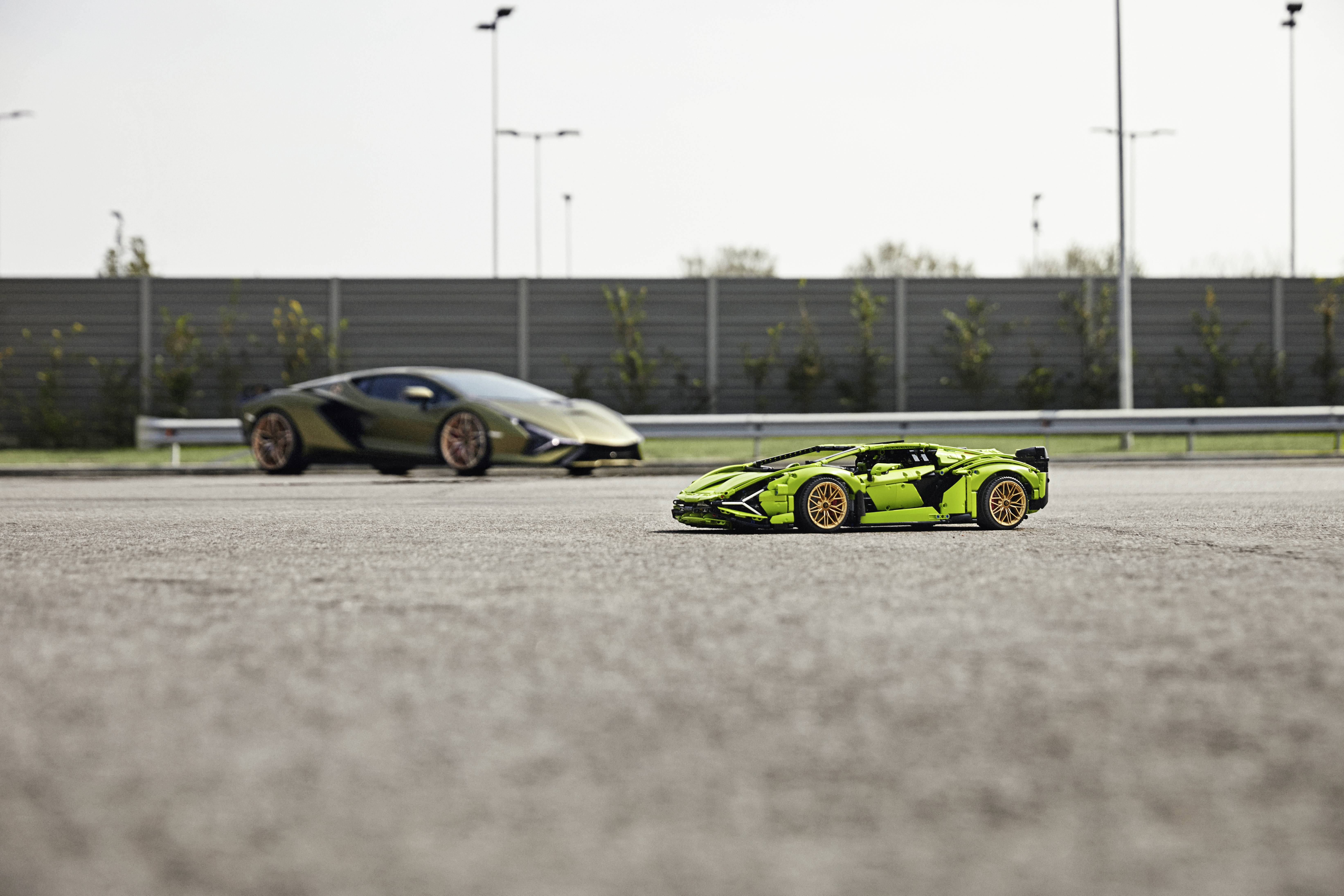 Zwei Sportwagen auf einer Straße, ein grüner im Vordergrund und ein goldener im Hintergrund, geparkt auf einem leeren Parkplatz.