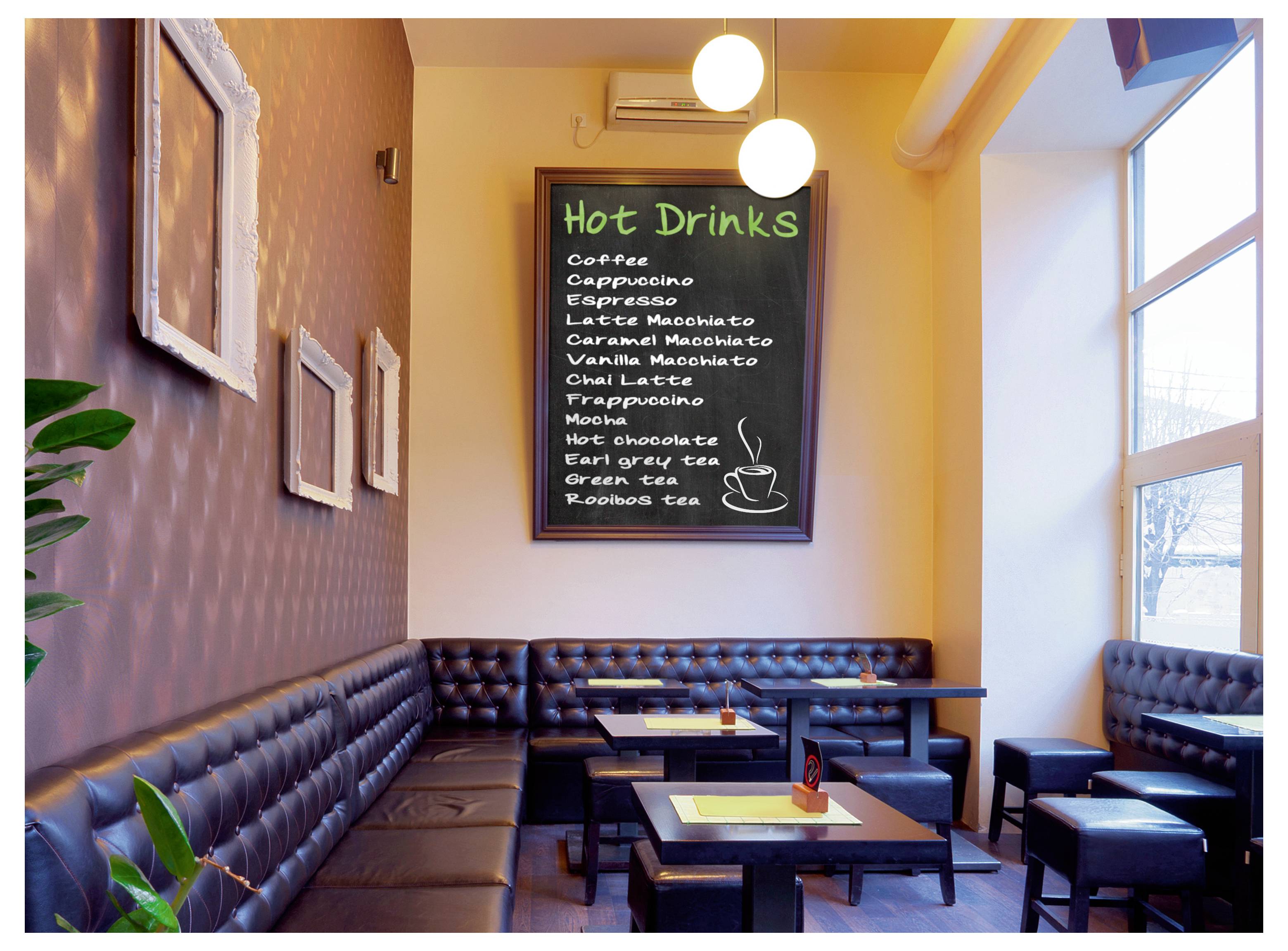 Gemütlicher Cafébereich mit schwarzen Lederbänken und Tischen unter einer Tafelmenü-Tafel mit der Aufschrift „Heiße Getränke", auf der Kaffee, Espresso, Tee und heiße Schokolade aufgelistet sind.