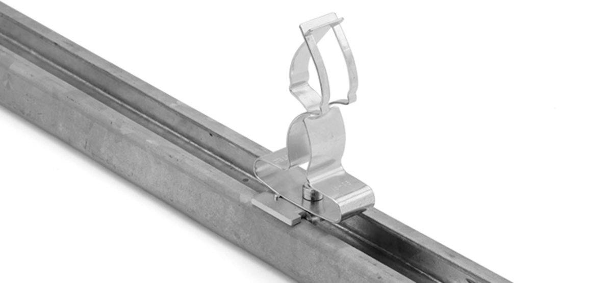 Metallklemme, die an einer Schiene befestigt ist, dient zur Sicherung und Führung von Kabeln oder Leitungen.