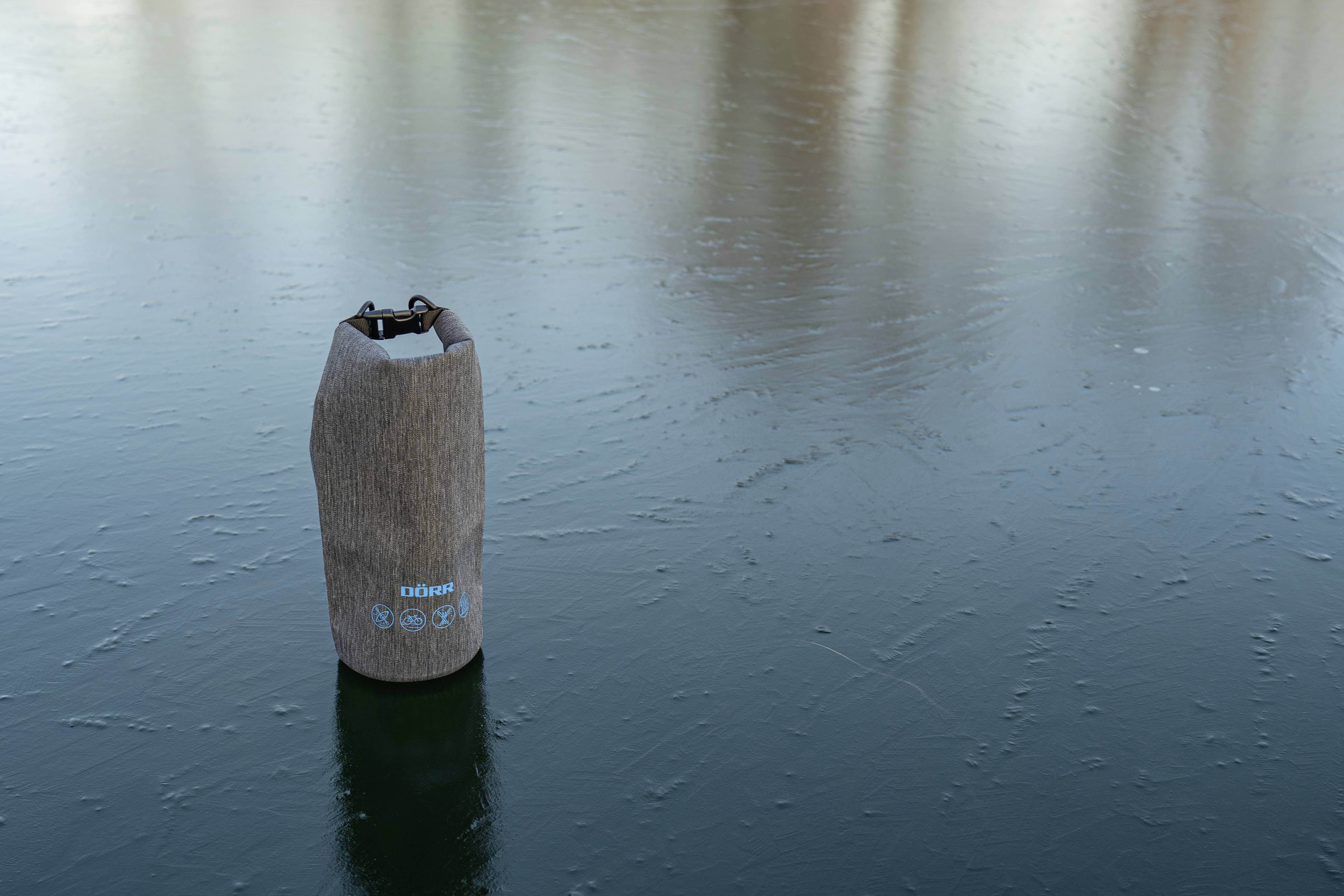 Eine braune wasserdichte Tasche steht auf einer gefrorenen Wasseroberfläche.