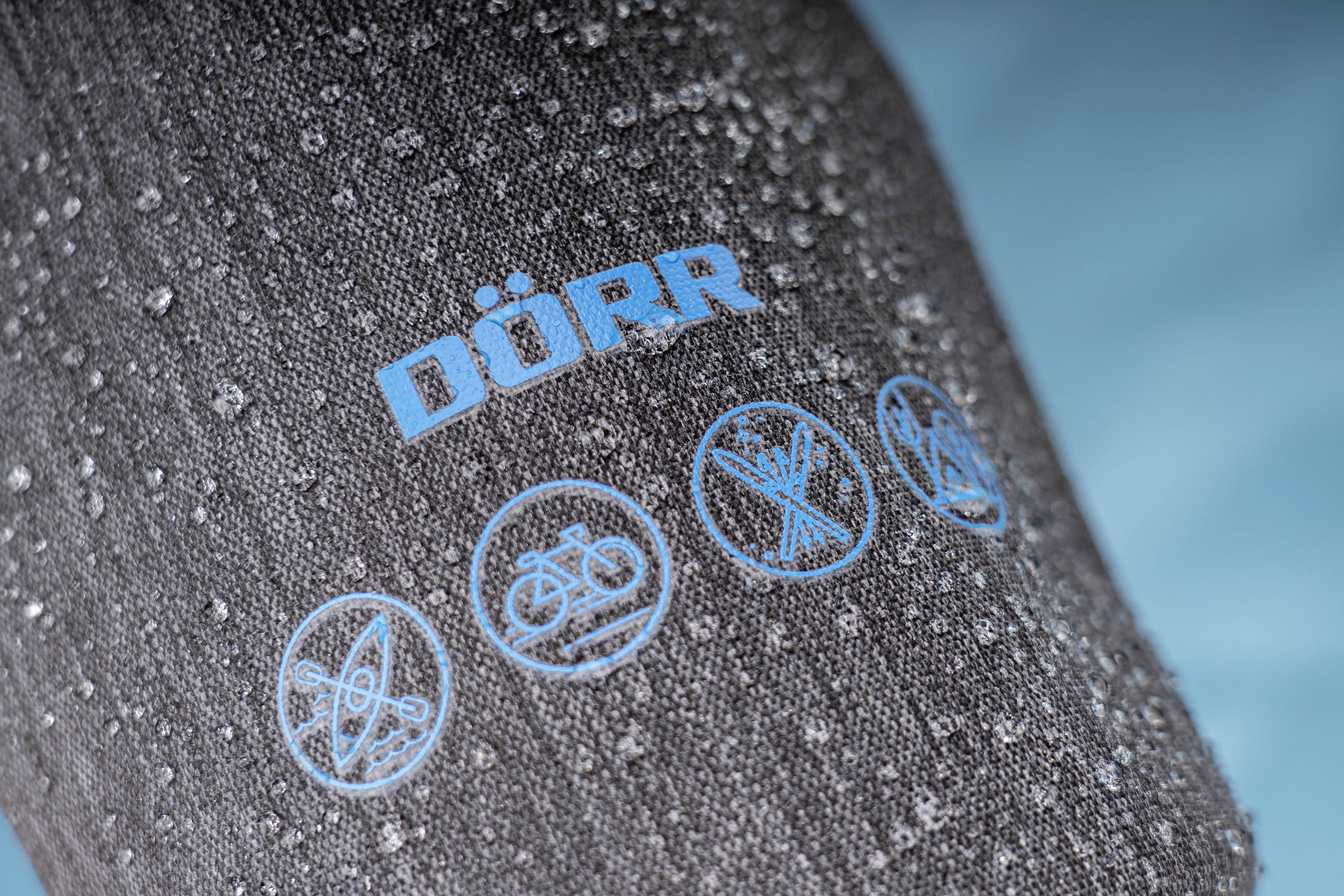Wassertropfen auf grauem Material mit blauem 'DÖRR'-Schriftzug und Symbolen für Outdoor-Aktivitäten: Kajak, Fahrrad, Wandern, Zelten.