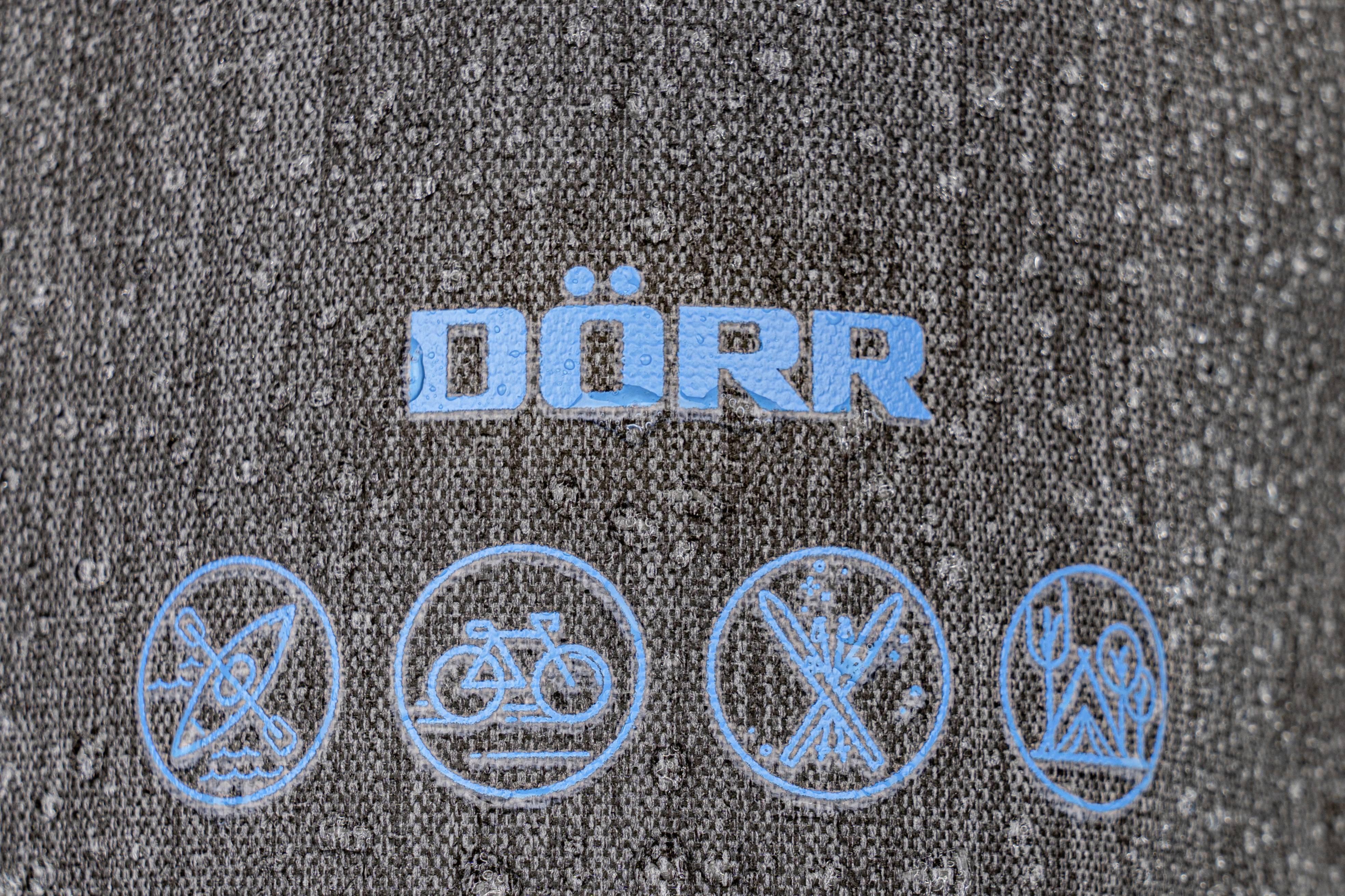 Grauer Stoff mit blauem Aufdruck 'DÖRR' und vier symbolischen Piktogrammen darunter.