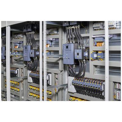 Ein offener Technikschrank zeigt eine komplexe Anordnung von Kabeln und elektrischen Komponenten in einem industriellen Kontrollsystem.