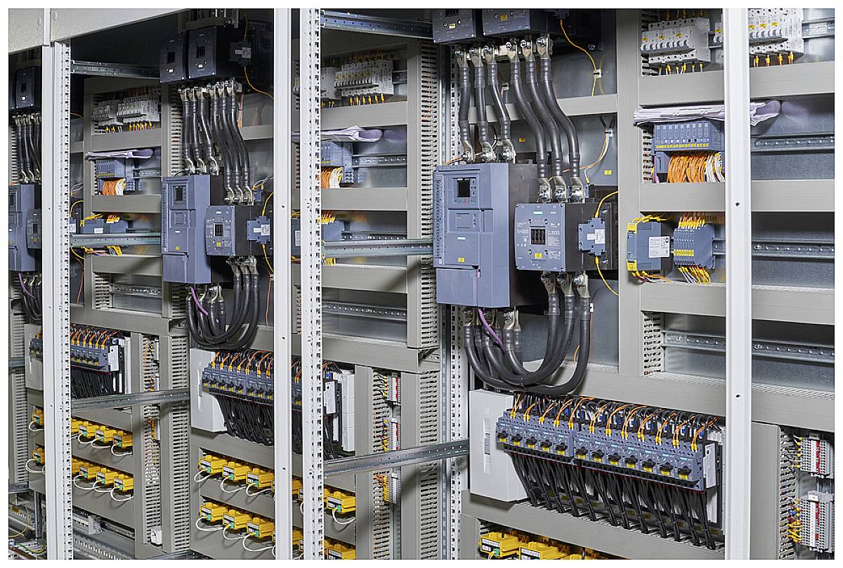 Ein elektrischer Schaltschrank mit mehreren Kabeln, Schaltern und Leitungen, die in geordneten Reihen für industrielle Steuerungen installiert sind.