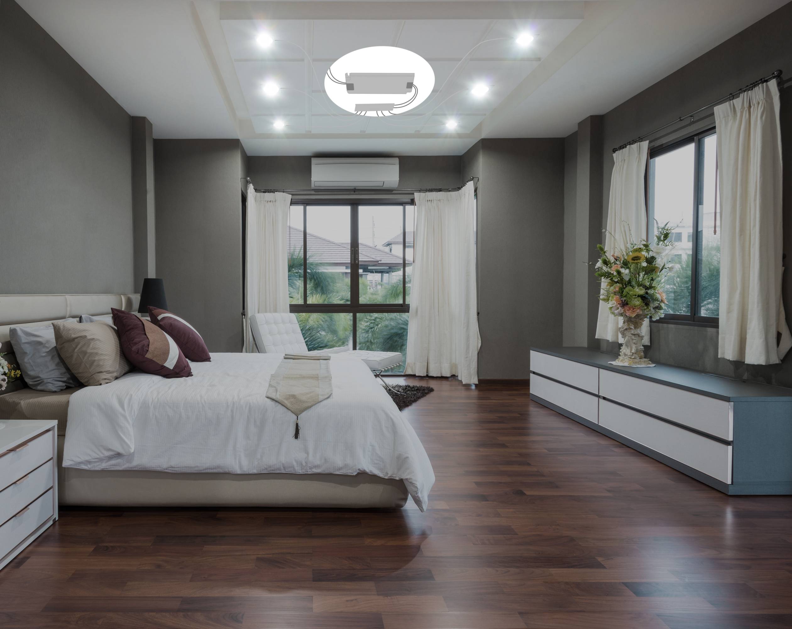 Ein modernes Schlafzimmer mit Doppelbett, weißen Vorhängen und Holzdielen, dekoriert mit Kissen und einer Blumenvase auf der Kommode.
