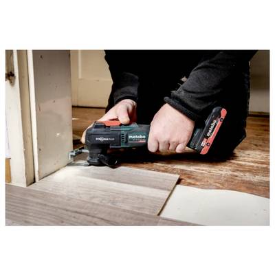 Eine Person benutzt ein Metabo-Elektrowerkzeug, um ein Stück Holzboden in der Nähe eines Türrahmens zu schneiden.
