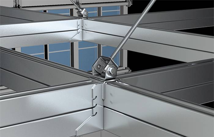 Metallischer Kreuzungspunkt von Rahmen mit Schraube in der Mitte, unterstützt durch diagonale Streben, vor einem Fensterhintergrund.