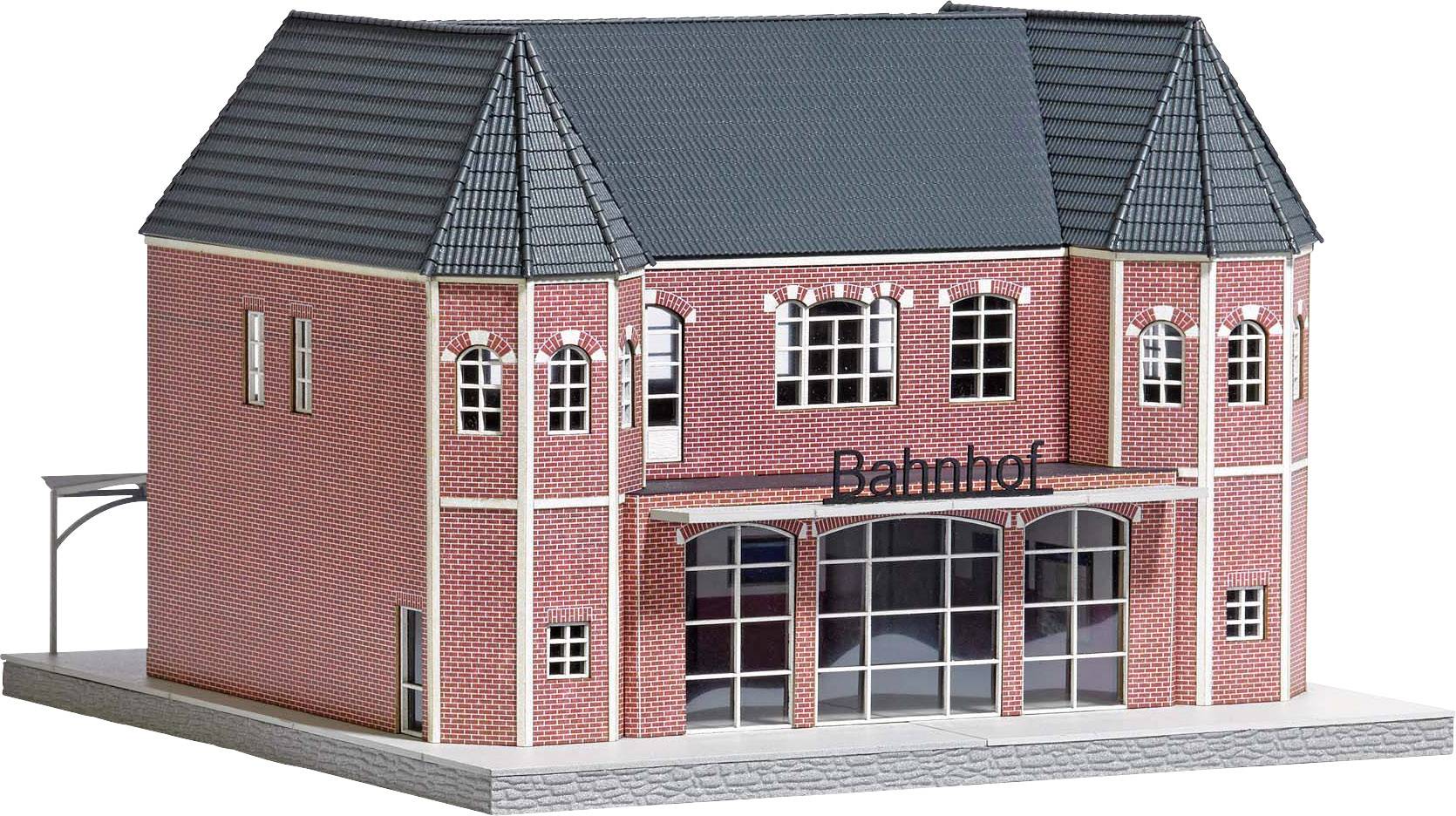 Ein Modell eines Bahnhofs mit rotem Backstein, hohen Fenstern und einem Schild mit der Aufschrift 'Bahnhof'.