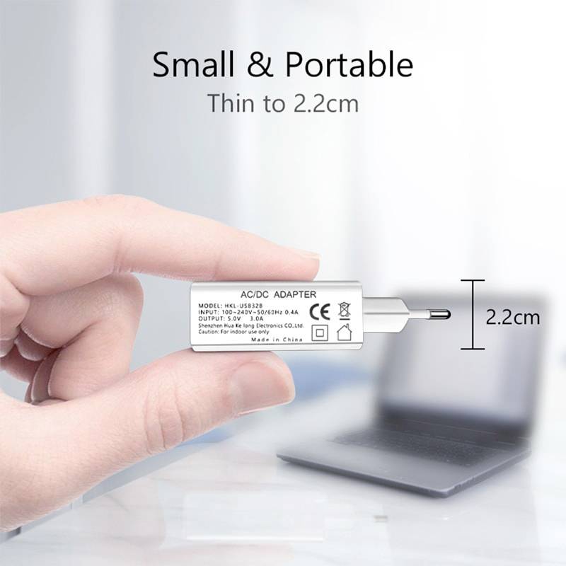 Eine Hand hält einen weißen AC/DC-Adapter vor einem unscharfen Laptop-Hintergrund. Text auf dem Bild: 'Small & Portable, Dünn bis 2,2 cm'.