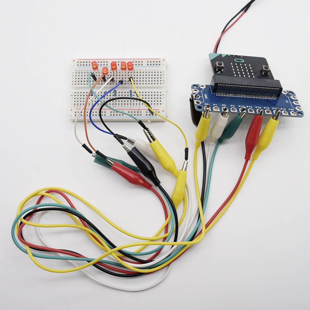Ein Steckbrett mit LEDs ist über mehrere Kabel mit einer Entwicklerplatine verbunden. Die Schaltung demonstriert eine elektronische Verbindung.