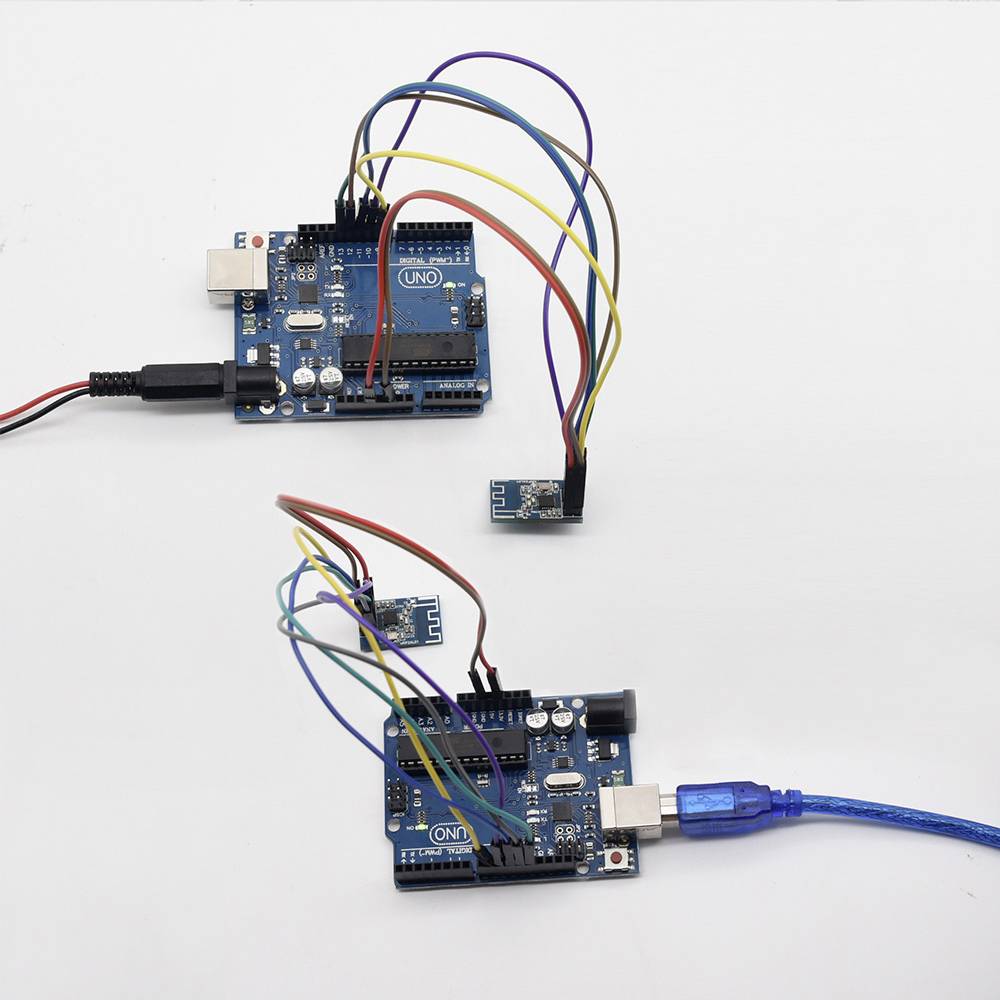 Zwei Arduino-Boards sind über Kabel und Steckmodule verbunden, auf einem weißen Hintergrund. Eines ist über USB angeschlossen.