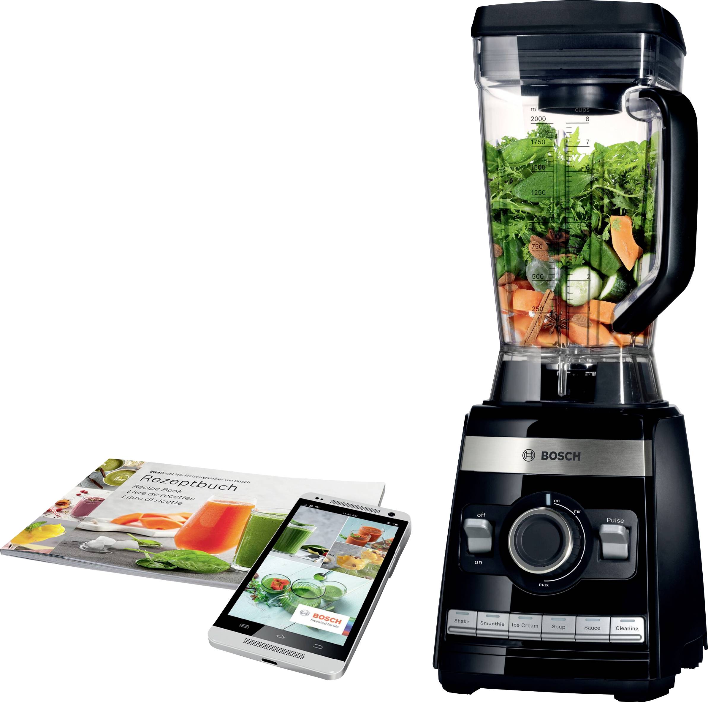 Ein schwarzer Standmixer gefüllt mit Gemüse steht neben einer geöffneten Broschüre und einem Tablet.