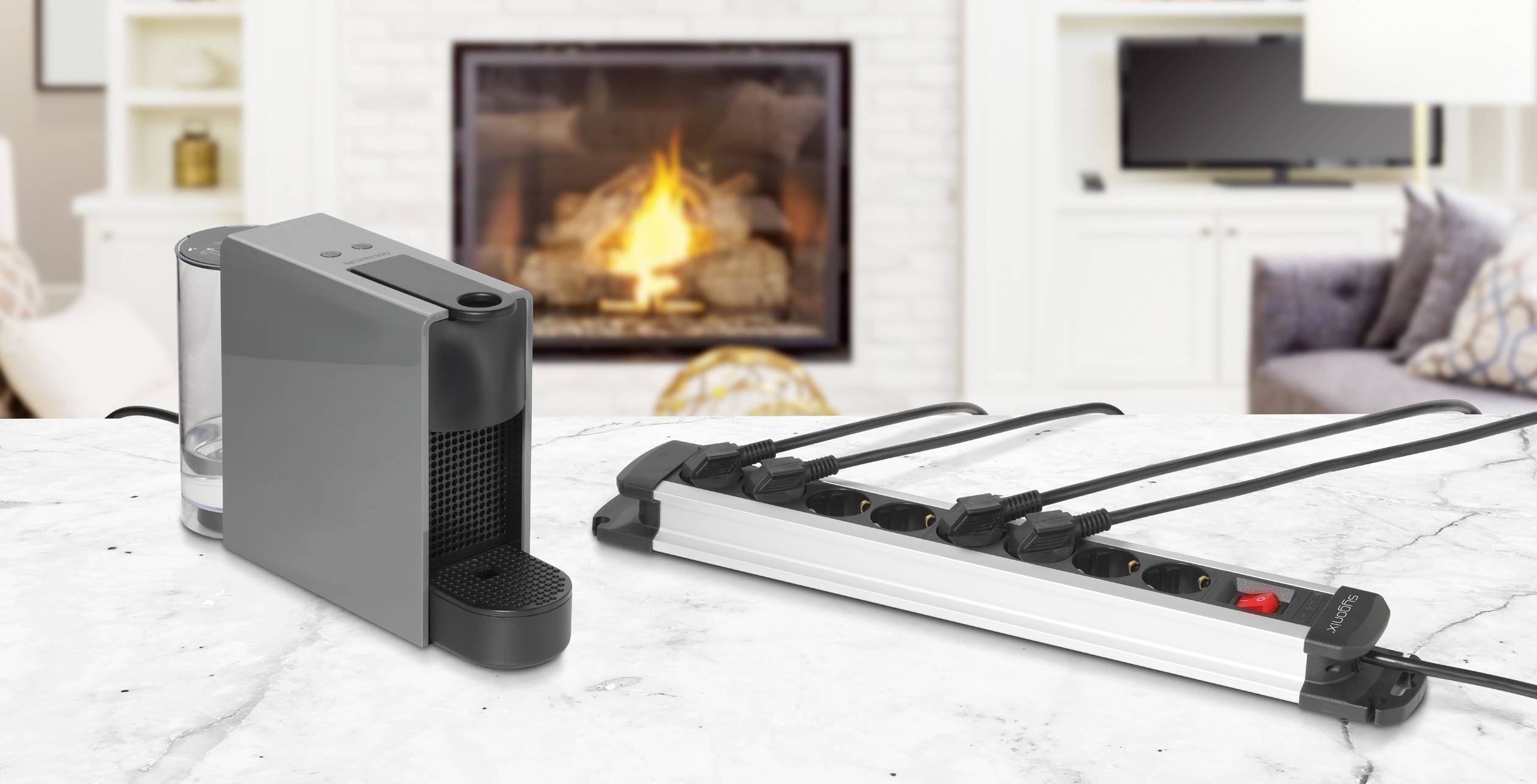 Auf einem Marmortisch stehen ein Luftbefeuchter und eine Steckdosenleiste. Im Hintergrund ist ein Kamin mit Feuer zu sehen.