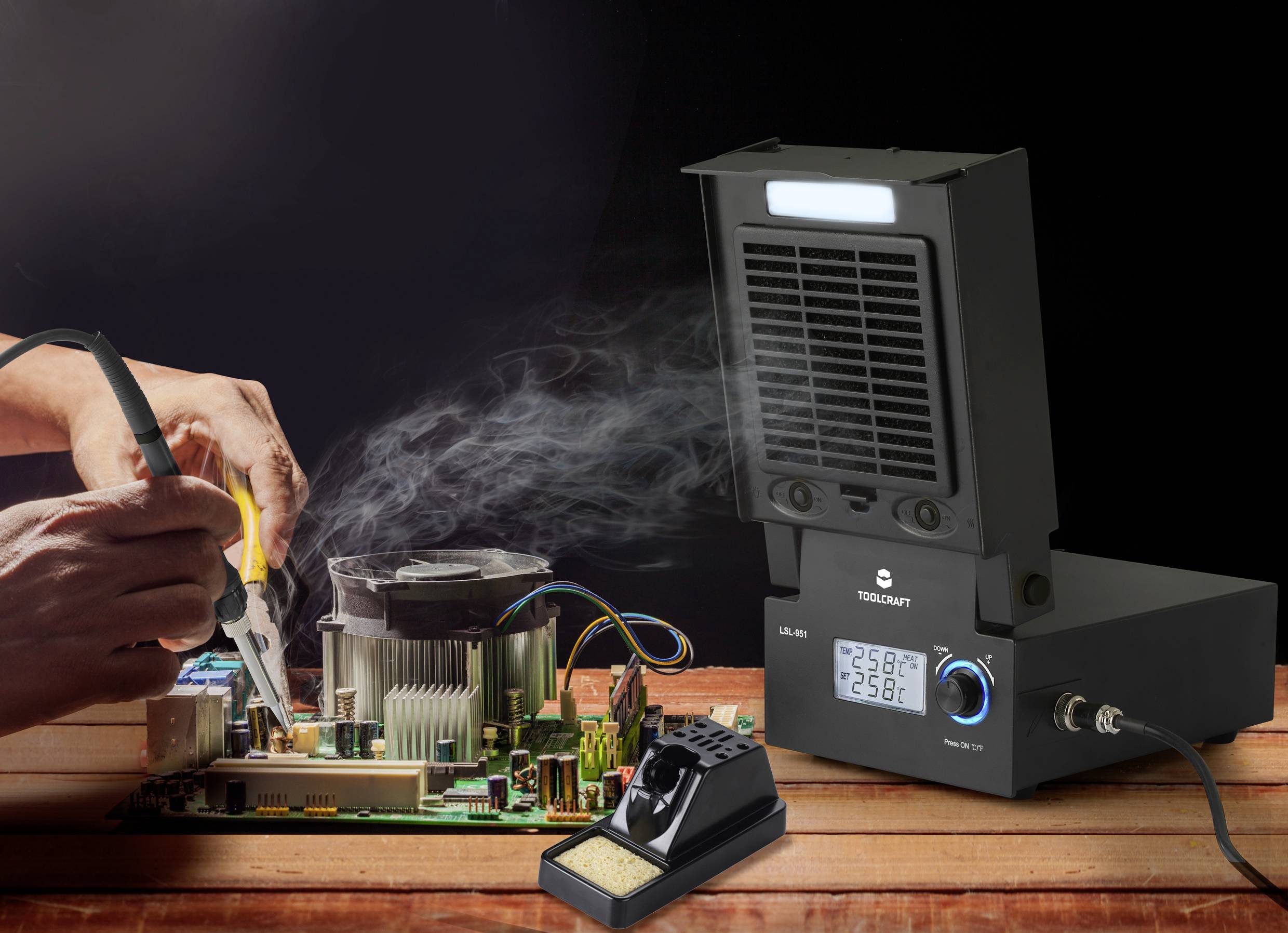 Eine Person lötet an einer Leiterplatte mit Rauchabsaugungsvorrichtung im Vordergrund. LCD-Anzeige des Geräts zeigt '25.6°C'.