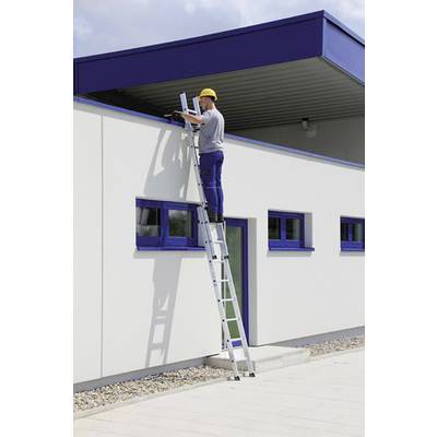 Eine Person steht auf einer Leiter und arbeitet am Dach eines modernen weißen Gebäudes mit blauen Fensterrahmen.