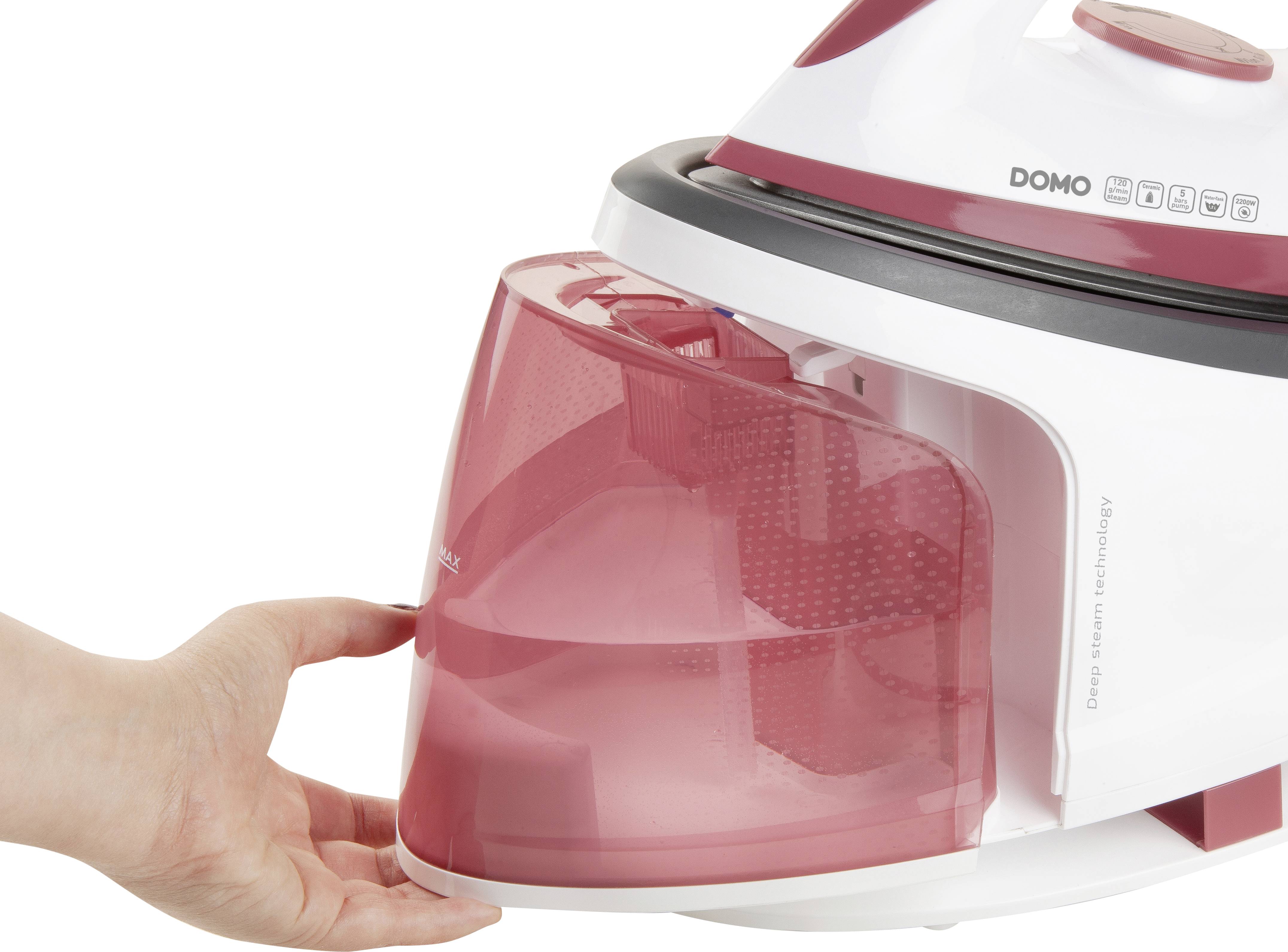 Ein Hand hält den roten Wasserbehälter eines weißen Dampfreinigers, der gelöst wird. Gerät trägt das Label 'DOMO Deep Clean Technology'.