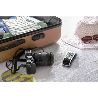 Offener Koffer mit Kleidung, Kamera, Batterieladegerät, Sonnenhut und Sonnenbrille auf einem Holztisch, bereit für die Reise.
