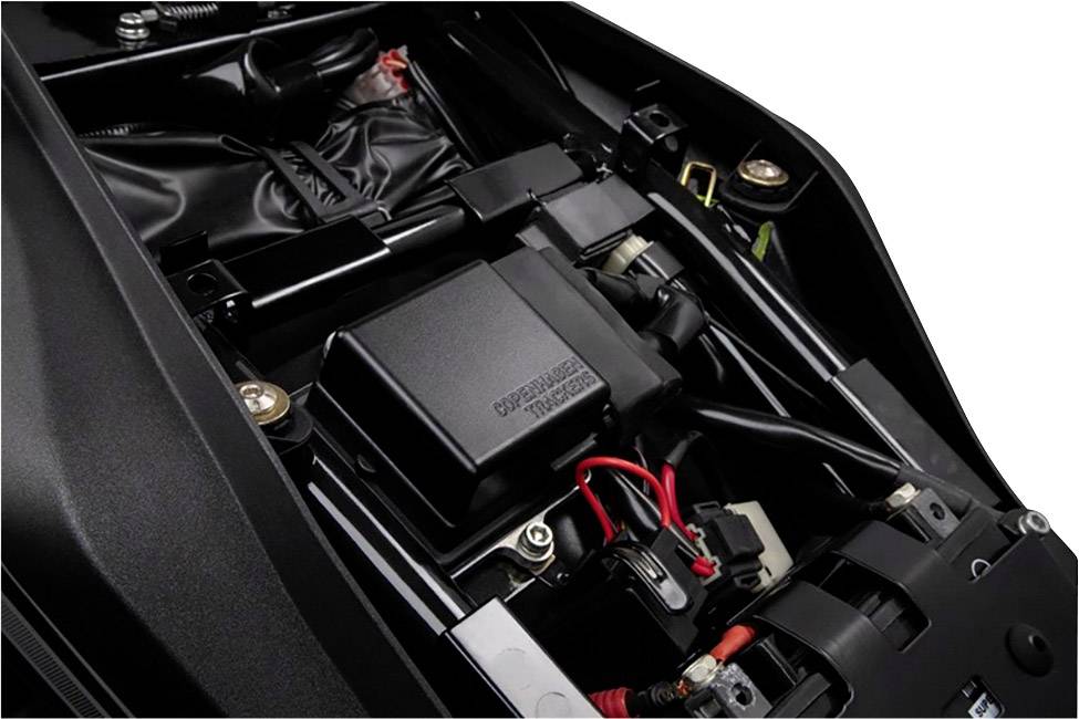 Ein Blick unter den Motorrad-Sitz zeigt die Batterie und Elektronikkomponenten. Kabel sind verbunden, einige Teile sind sichtbar befestigt.