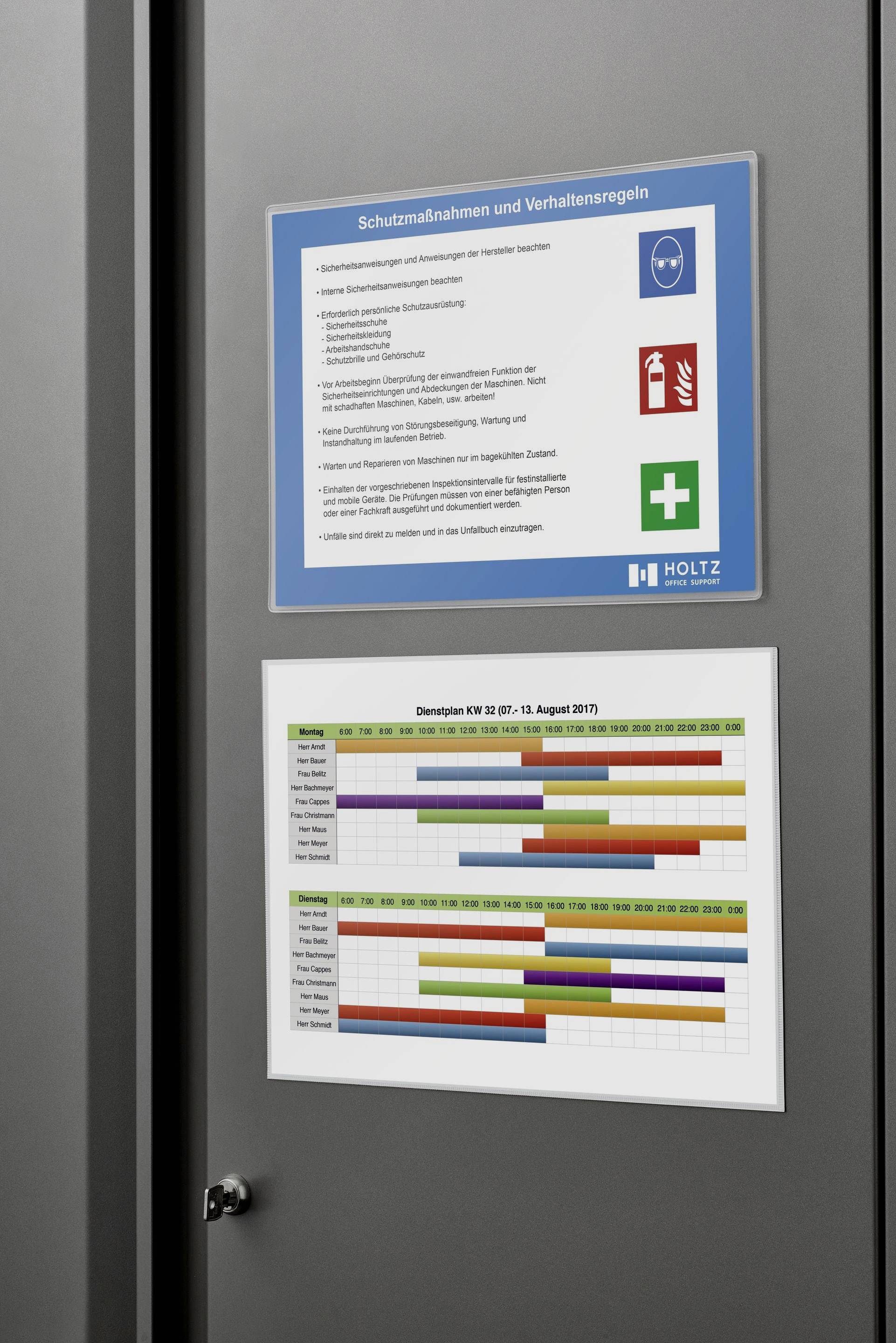 Ein Schild an der Wand zeigt 'Schutzmaßnahmen und Verhaltensregeln' mit Listen von Sicherheitsmaßnahmen und Symbolen für Sicherheit und Hygiene. Darunter zwei Diagramme mit farbigen Balken.