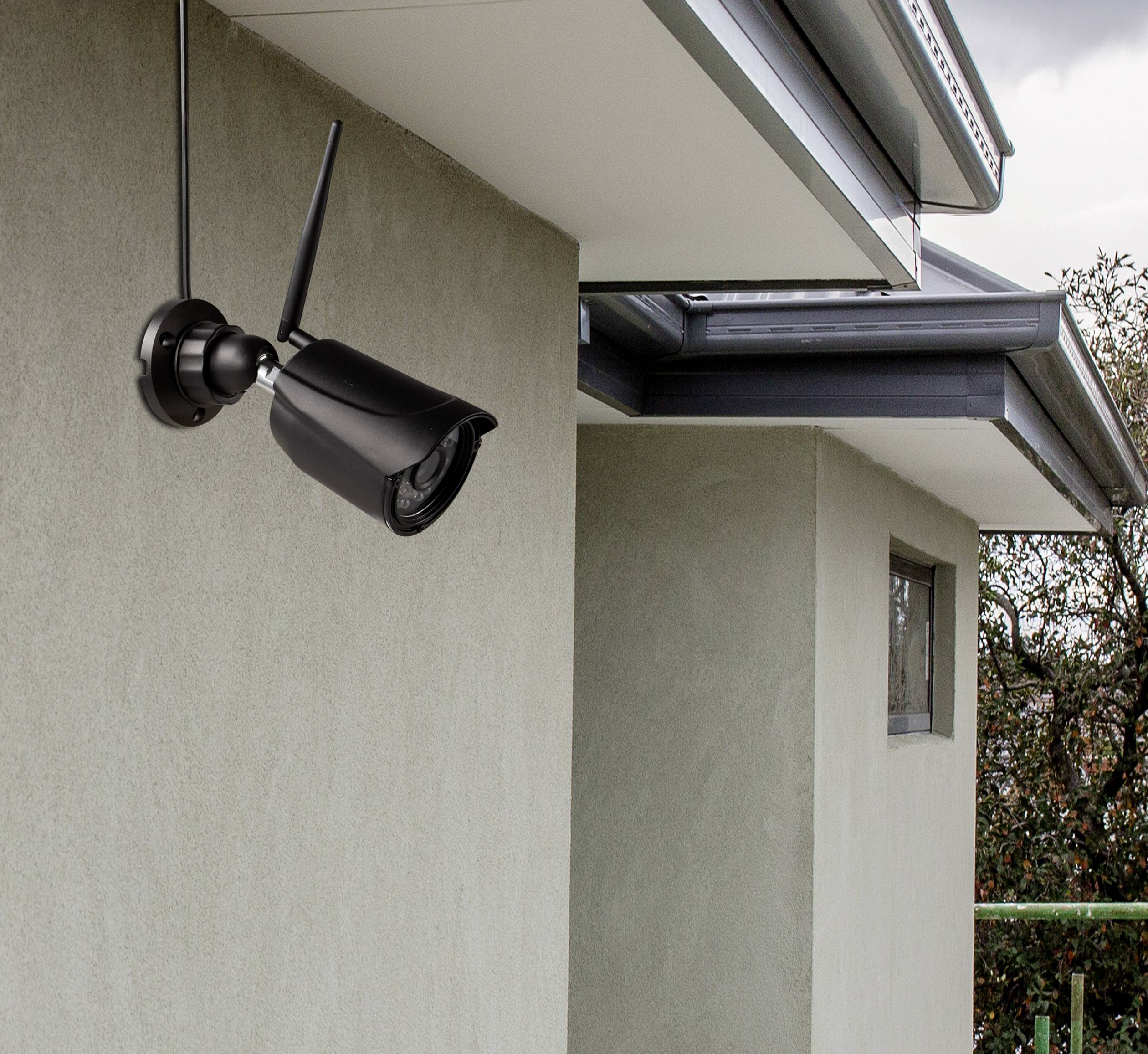 Überwachungskamera an einer modernen Hauswand installiert, zeigt Richtung Garten, um Sicherheitsüberwachung zu gewährleisten.