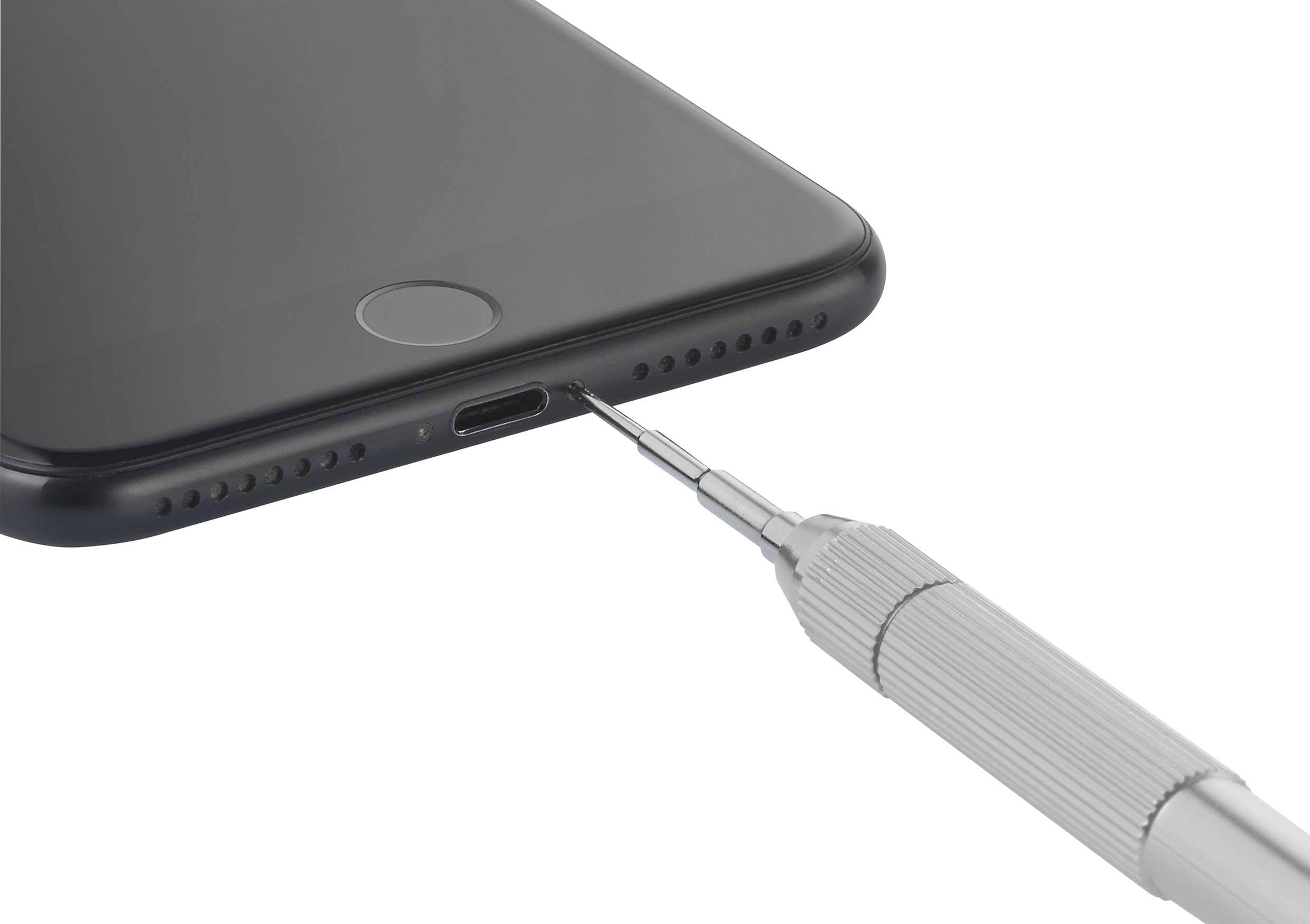 Ein Schraubendreher nähert sich dem Ladeanschluss eines Smartphones von unten, um die Schrauben zu lösen oder zu befestigen.