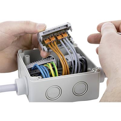 Jemand installiert Drähte in einer Verteilerdose. Die farbigen Kabel werden in Klemmen geführt, um elektrische Verbindungen herzustellen.