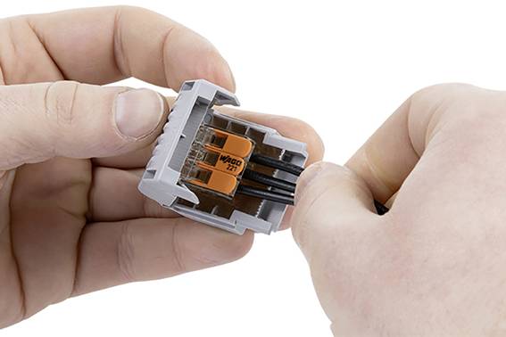 Zwei Hände verbinden Kabel mit einem grauen und orangen Kabelverbinder.