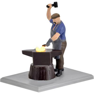 Ein Mann in Arbeitskleidung schmiedet Eisen auf einem Amboss und schlägt mit einem Hammer. Das Eisen leuchtet gelb vor Hitze.