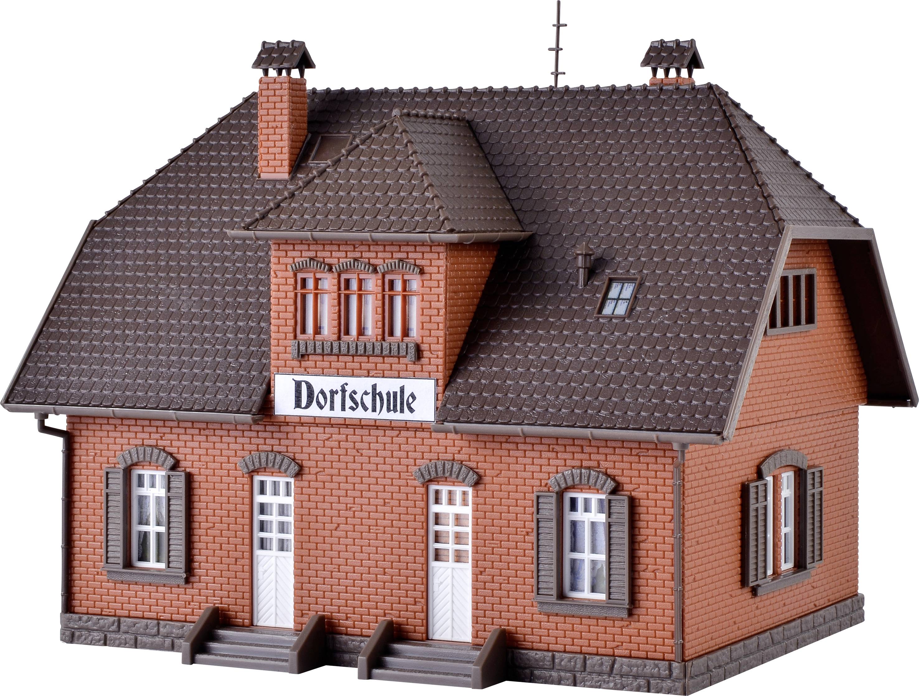 Ein rotes Modellhaus mit der Aufschrift 'Dorfschule' zeigt die Frontansicht eines traditionellen Gebäudes mit drei Türen und mehreren Fenstern.